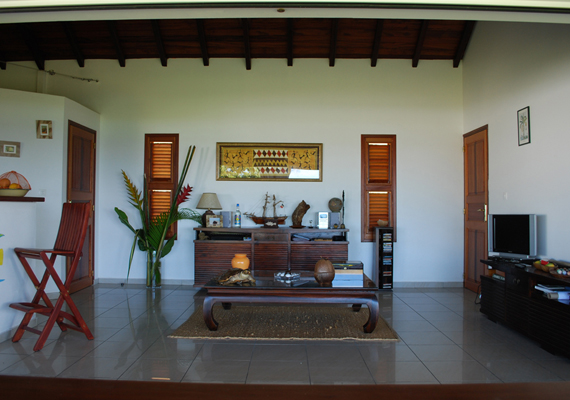 Salon totalement ouvert sur la terrasse avec à gauche la cuisine et à droite un accès à la chambre jaune.