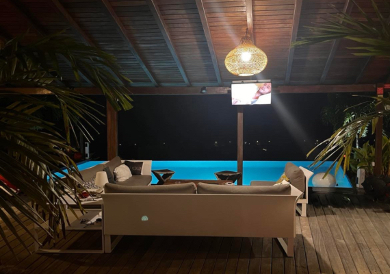 Salon extérieur avec télévision, accès piscine et vue exceptionnelle.